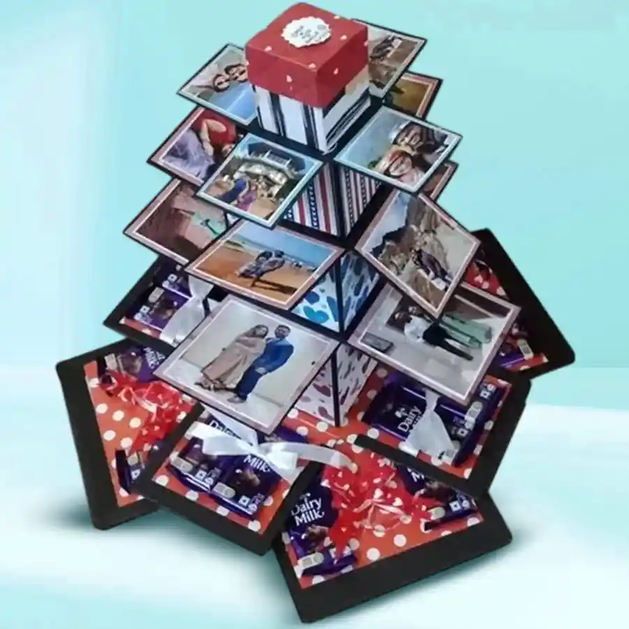 A colorful 7 Layer Tower Explosion Box filled with chocolates and photographs, topped with a personalized message box.