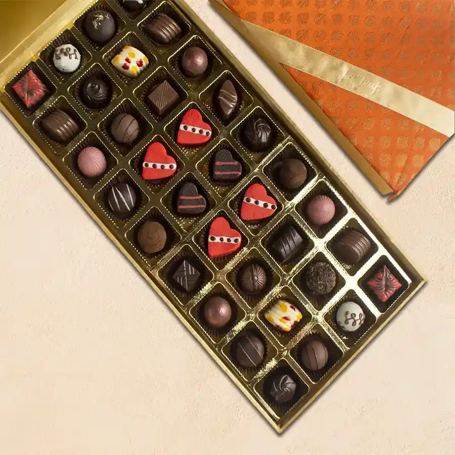 A beautiful silk box filled with an assortment of 32 assorted truffles and 4 heart-shaped marzipan truffles, elegantly presented for gifting.