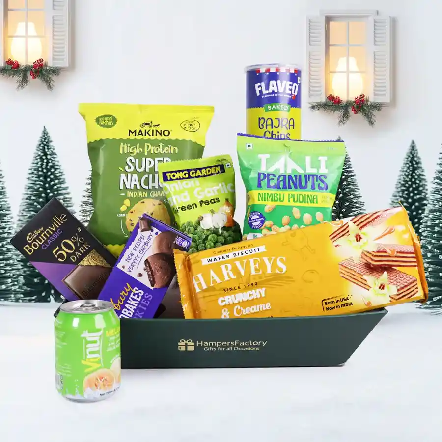 A festive Christmas Snack N Treats Basket filled with savory and sweet treats like nachos, chips, chocolate, and melon juice, perfect for sharing.