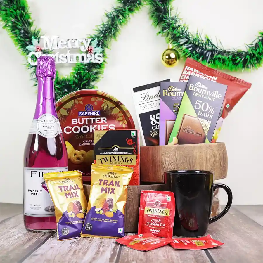 A festive collection of snacks including drinks, teas, cookies, chocolates, and gourmet popcorn, beautifully presented in a black mug and reusable basket.