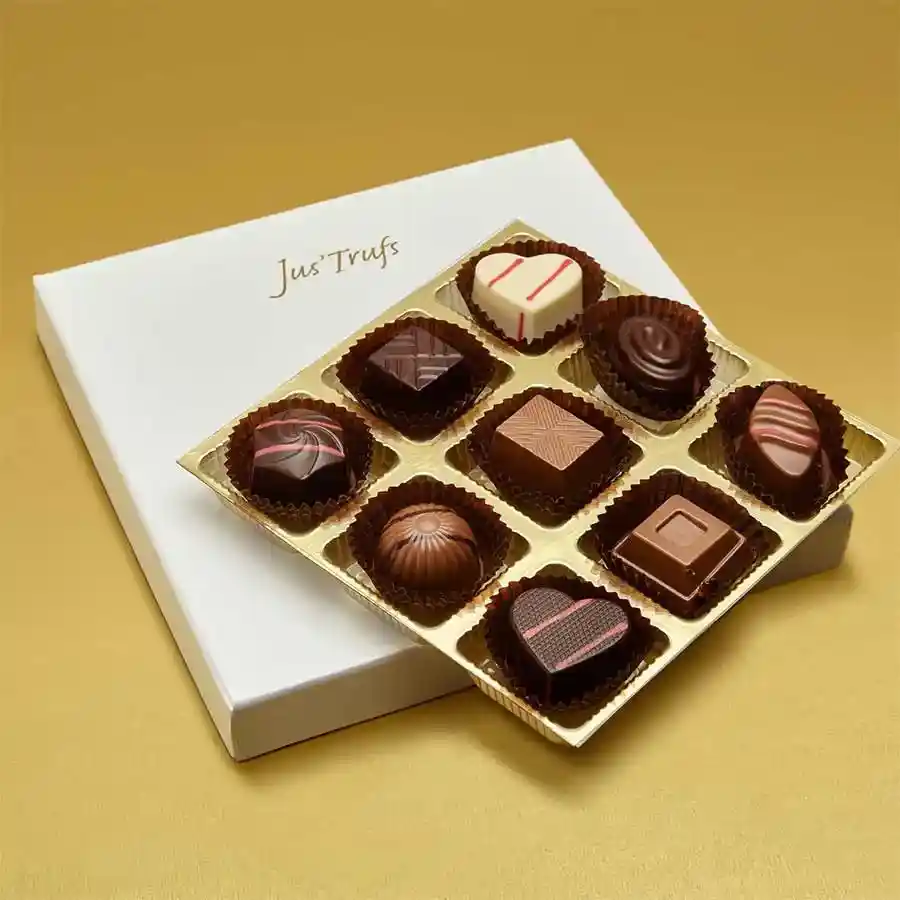 A beautifully arranged gift box containing nine handcrafted truffles in various flavors, set against an elegant backdrop.