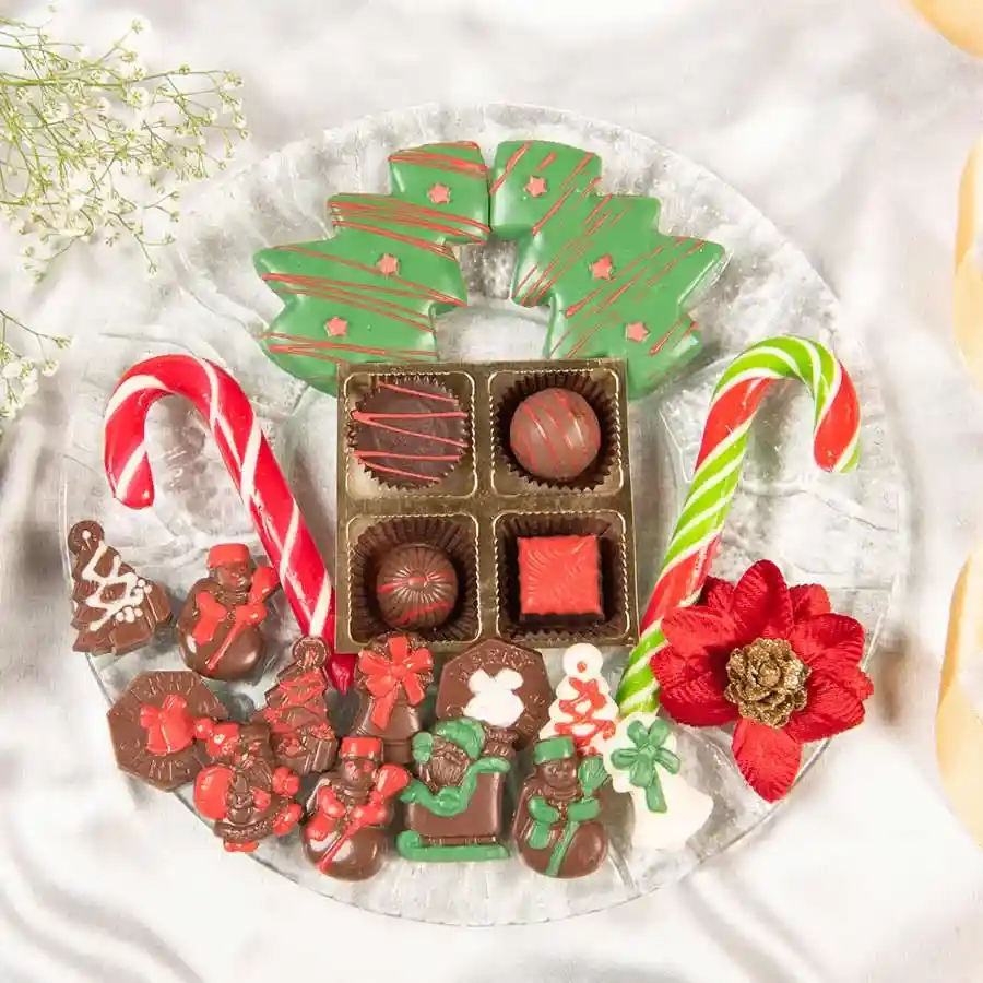 Merry Treats Celebration Tray featuring chocolate-coated Christmas tree butter cookies, assorted truffles, candy canes, and chocolate shapes on a glass platter