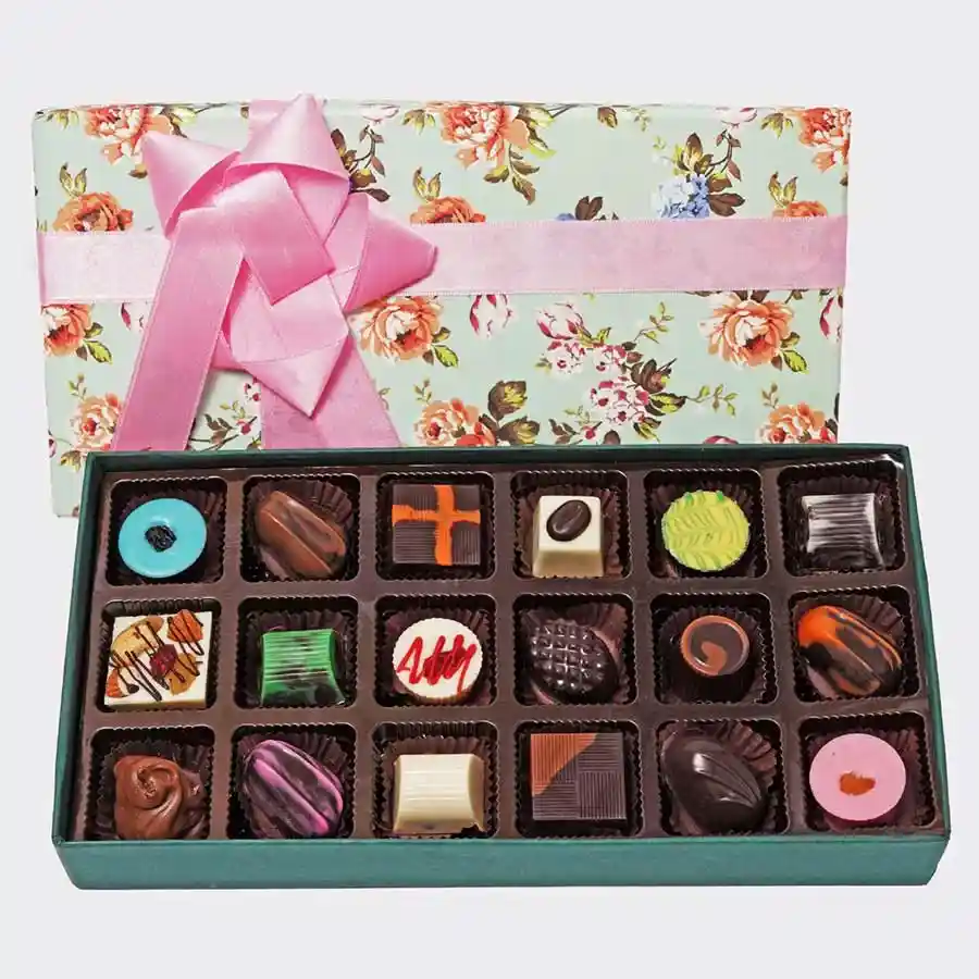 An elegant selection box containing 18 assorted chocolates in various shapes and colors, including hazelnut, butterscotch, lemon, mint, almond rock, and coffee flavors, beautifully arranged for gifting or personal indulgence.