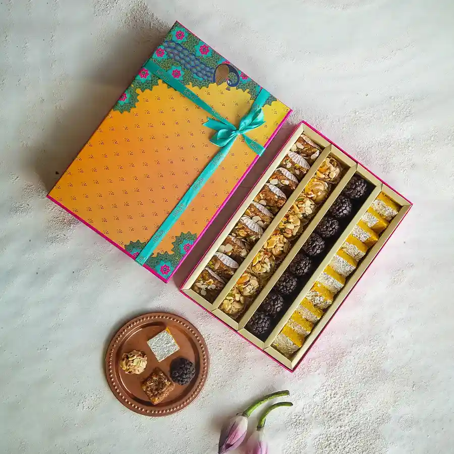 Kesar Special Assorted Sweets Gift Box featuring Dodha Barfi, Moong Thal, Chocochip Laddoo, and Dry Fruit Laddoo.