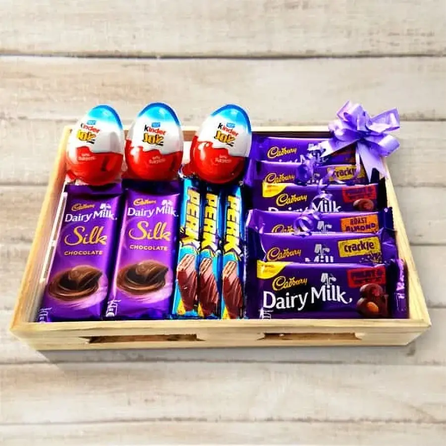 A beautifully arranged wooden tray filled with assorted chocolates including Kinder Joy, Cadbury Perk, and various Dairy Milk varieties.