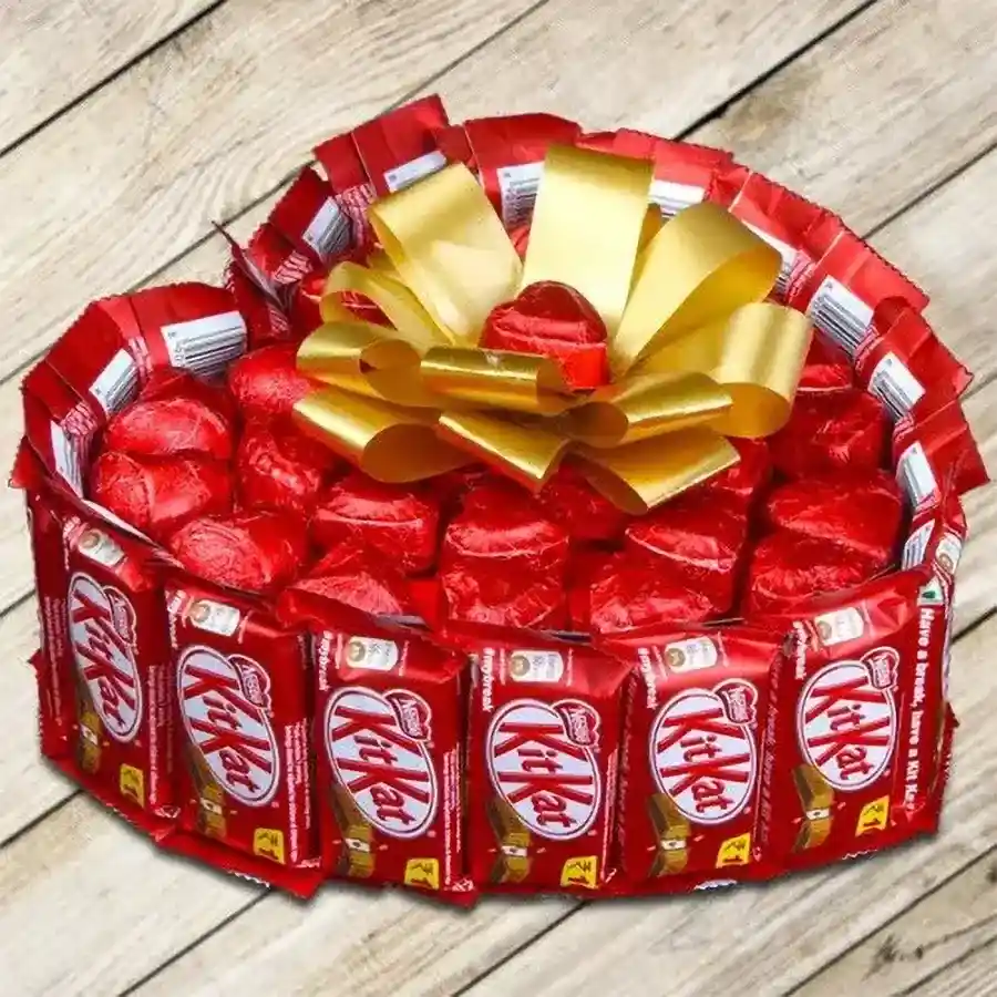 Heart-shaped arrangement featuring 20 KitKat bars and 24 assorted handmade heart-shaped chocolates tied with a golden ribbon bow.