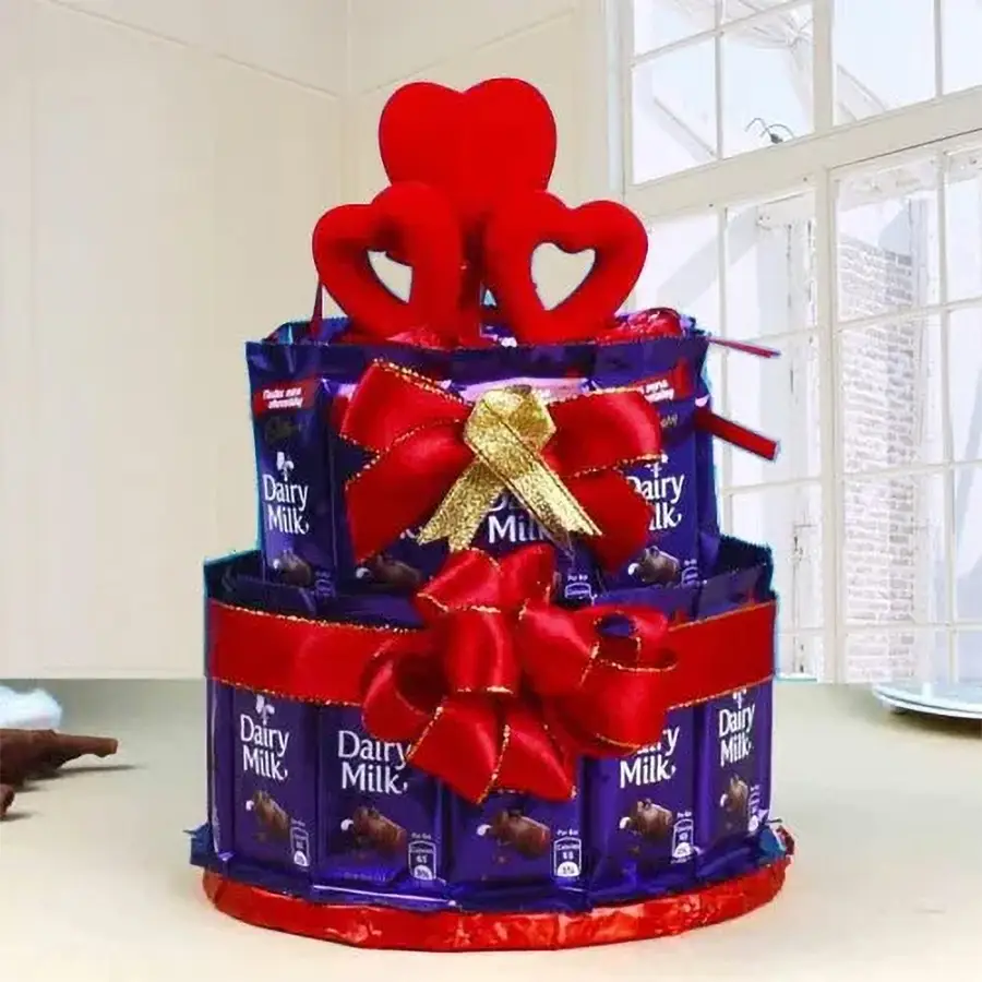 Two-tier chocolate arrangement with 25 Cadbury Dairy Milk pieces and 100g of handcrafted heart-shaped chocolates, decorated with elegant ribbons.