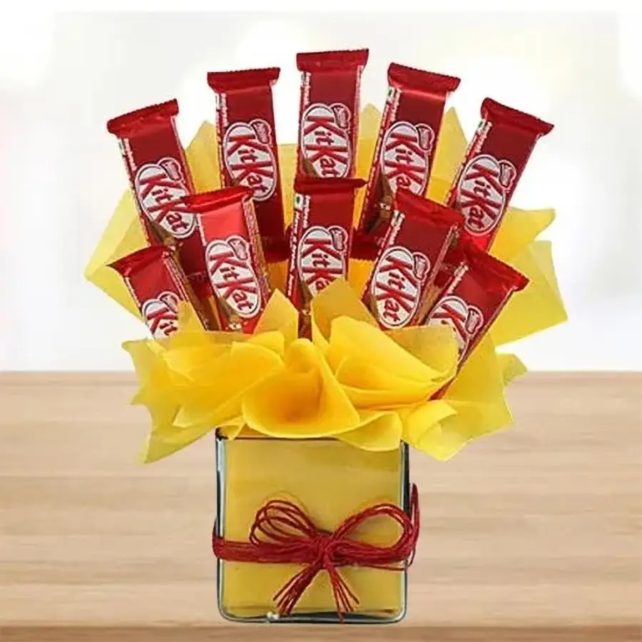 Arrangement of ten KitKat bars wrapped in yellow tissue, displayed in a sleek glass vase.