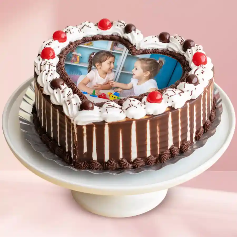 Heart-shaped Black Forest cake with cream, chocolate sprinkles, cherry, and personalized photo.