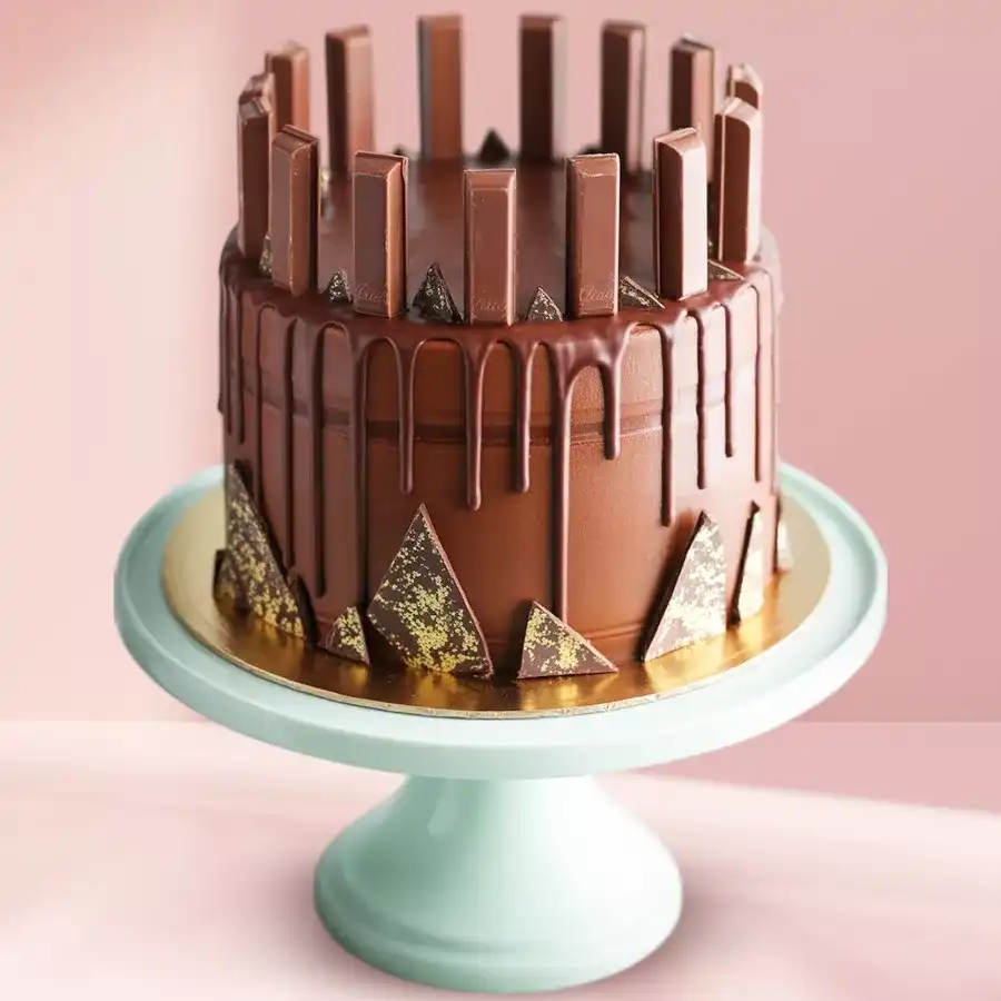 Eggless chocolate cake with Kitkat bars, white frosting, and chocolate glaze, perfect for gifting special occasions.