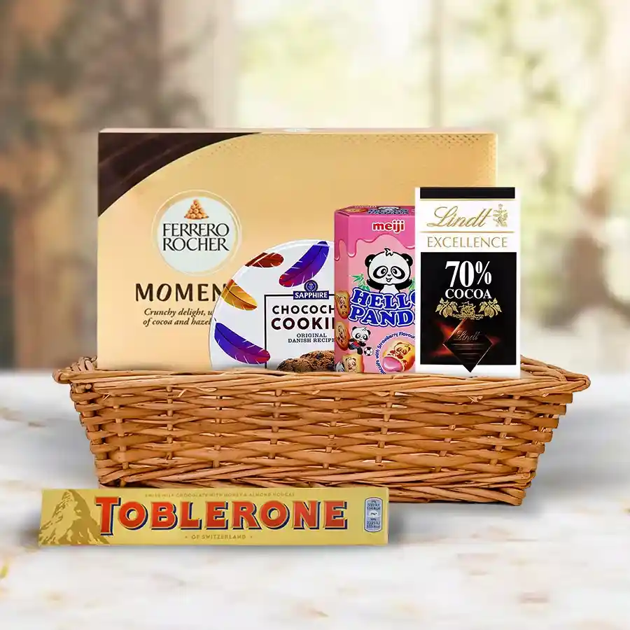 Yummy Chocolate Hamper featuring Ferrero Moments, Toblerone Bar, Lindt Dark chocolate, Meloji Hello Panda biscuits, arranged in a charming basket and Sapphire Tin.