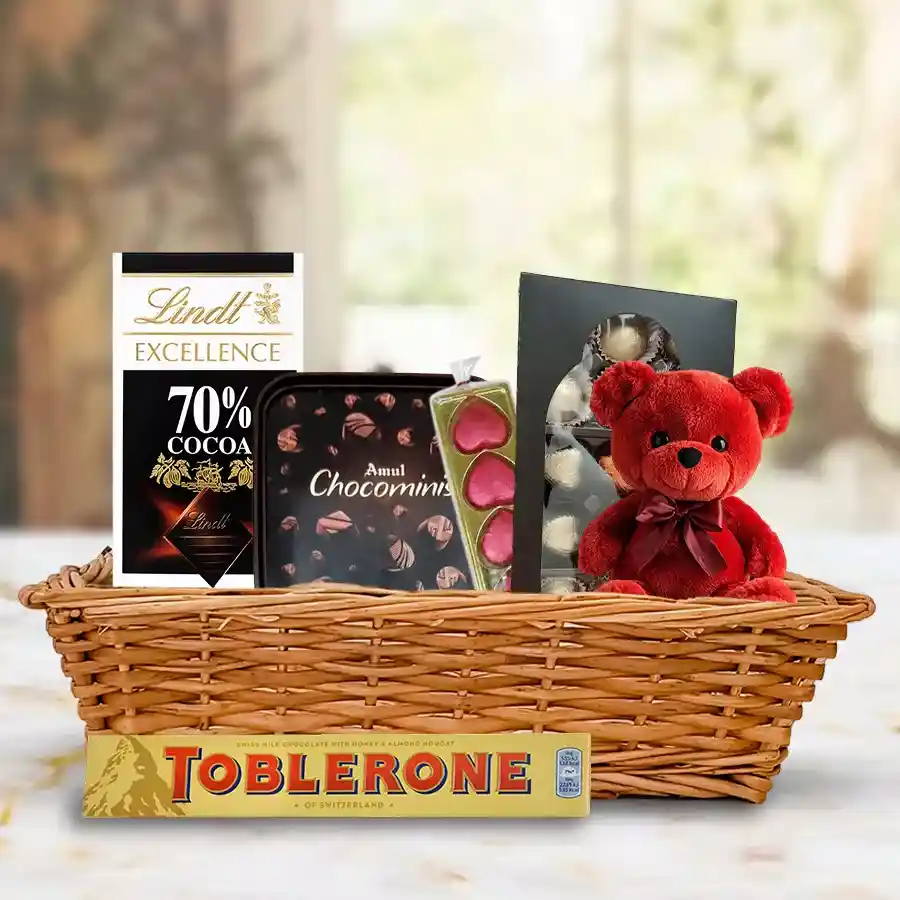 Wonderful chocolate gift basket with a 6-inch teddy, filled with Toblerone, heart-shaped chocolates, Amul Choco Minis, and Lindt Excellence bars, beautifully arranged in a charming small basket.