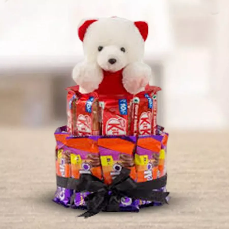 Chocolate bars and a teddy bear arranged together in a gift package.