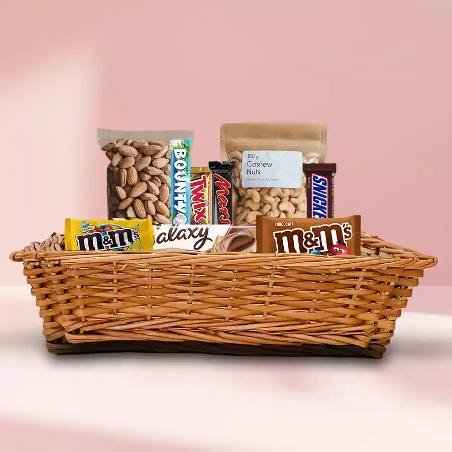 Tasty Dry Fruits and Imported Chocolates Gift Hamper in a cane basket with almonds, cashews, Twix, Snickers, Mars, Bounty, Galaxy, and M&M’s