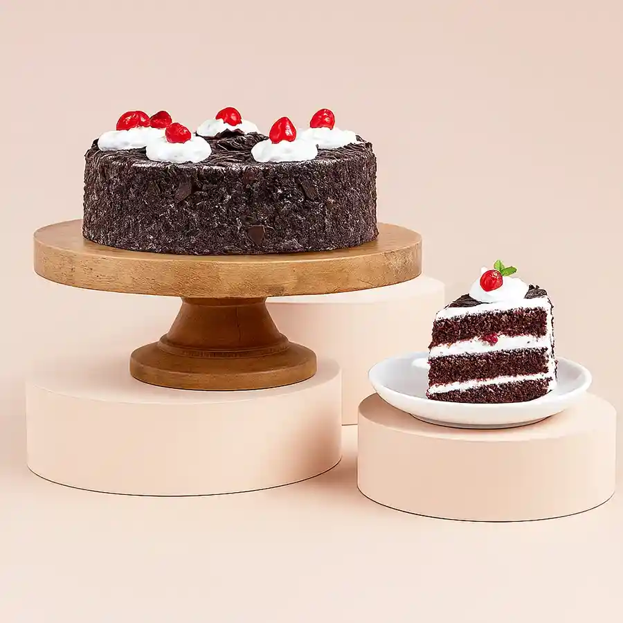 La Chocolate's Black Forest Cake featuring layers of chocolate sponge, whipped cream, and cherries, elegantly adorned with chocolate shavings.