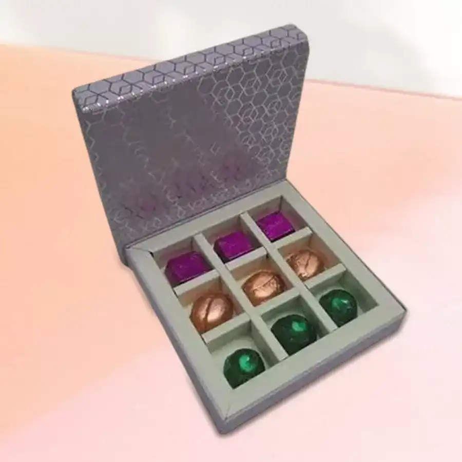 A beautifully arranged box of Toothsome Handmade Chocolates Treat featuring 9 unique chocolate pieces with various flavors like Paan, Fruits & Nuts, and Roasted Almonds.