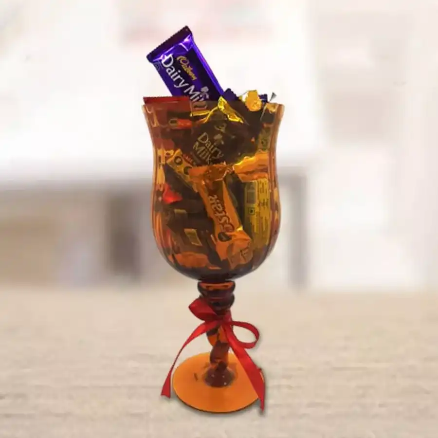 Yummy Assorted Chocolates Trophy in a glass vase filled with Cadbury Dairy Milk bars, Cadbury Five Stars, and Nestle KitKats, tied with a ribbon