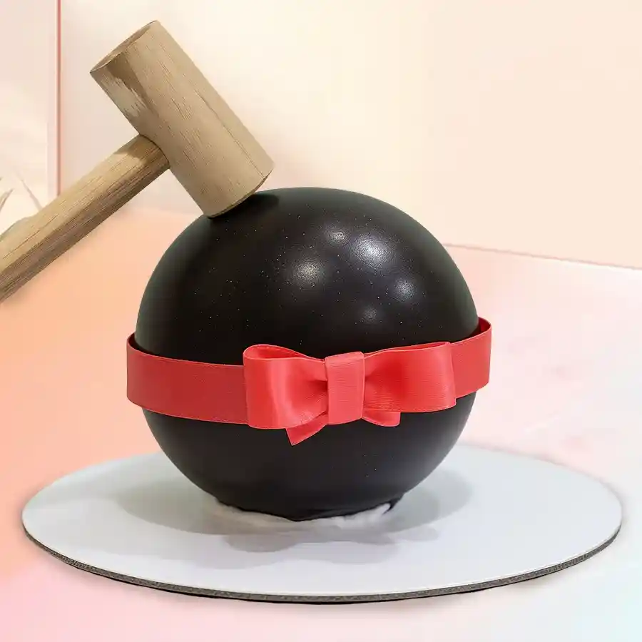 A 1 lb chocolate ball smash cake accompanied by a hammer for an exciting dessert experience.