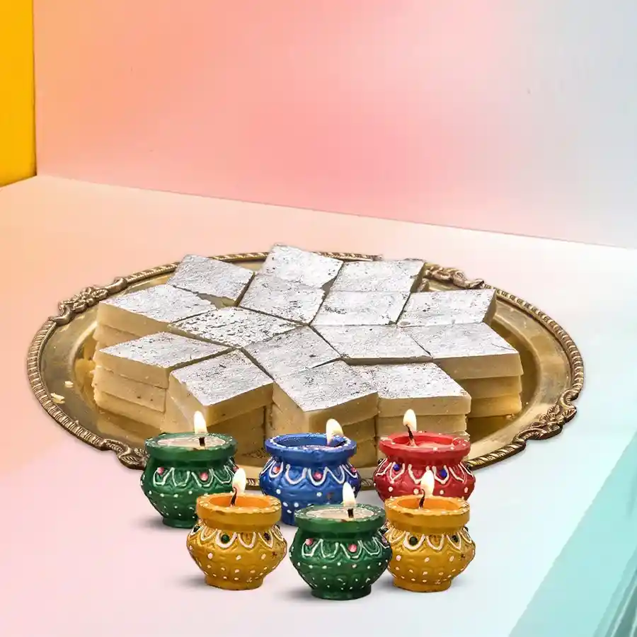 Assorted Kaju Katli and six wax diyas in a festive set.