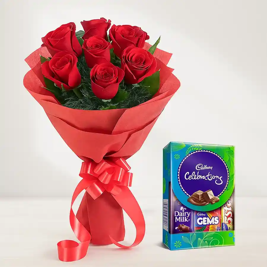 A stunning bouquet of red roses wrapped in tissue with a Cadbury Mini Celebrations Pack, perfect for gifting.