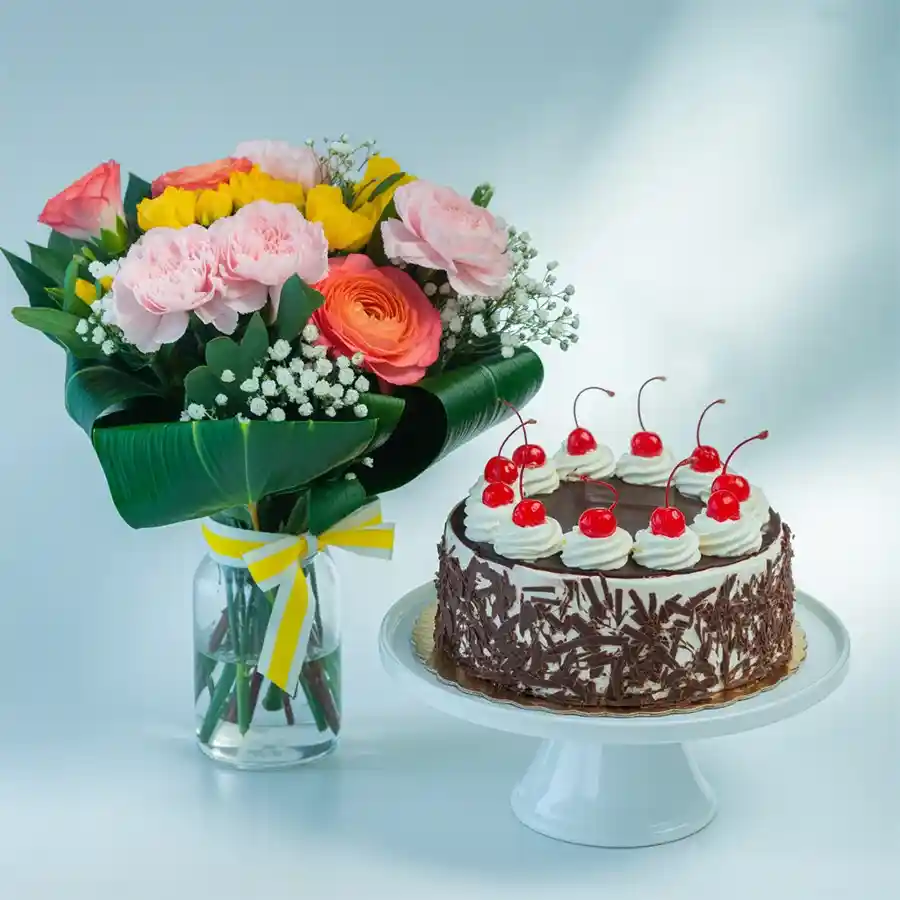 A delectable Black Forest cake paired with a vase of 24 mixed flowers, including roses and carnations, perfect for celebrations.