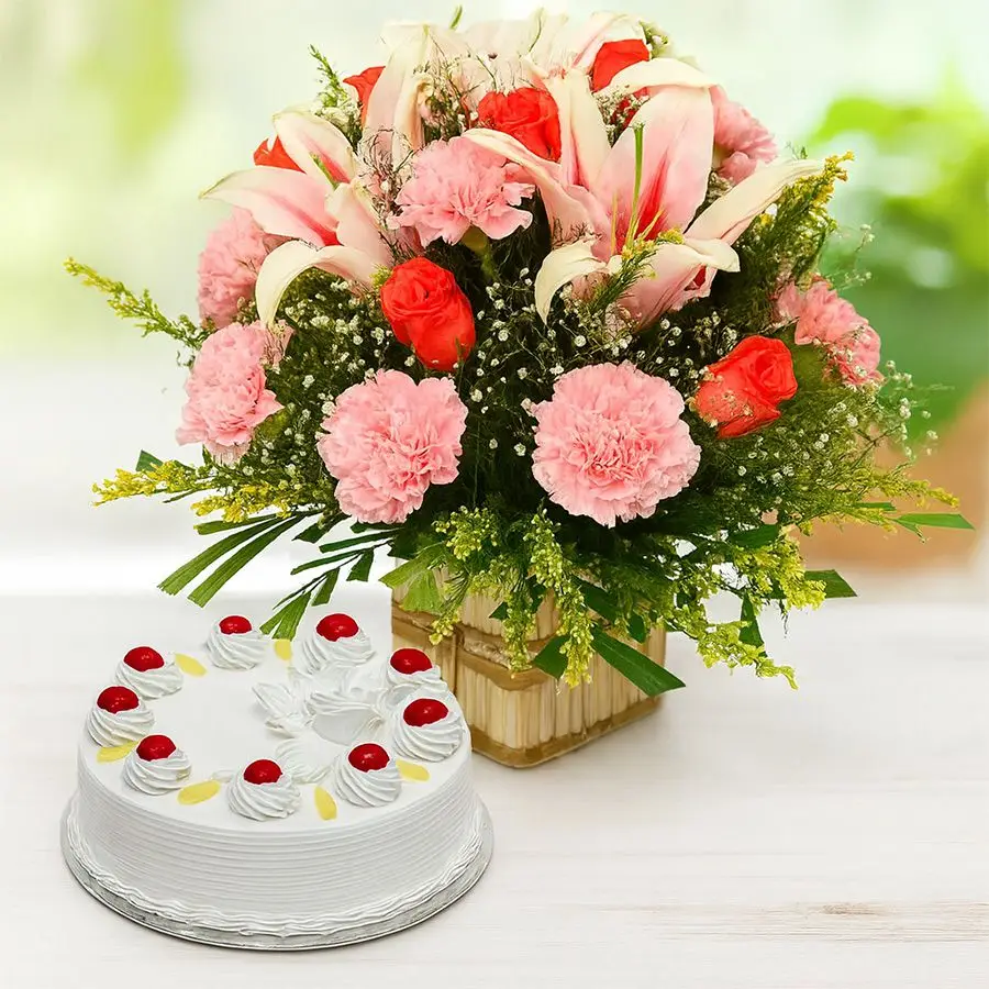A vibrant basket of mixed flowers with pineapple cake, featuring 12 carnations, 6 roses, and 4 lilies, perfect for celebrating special moments.