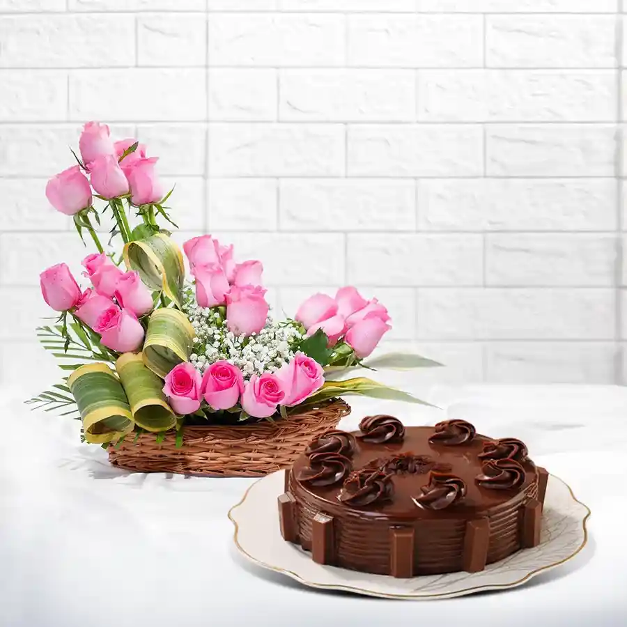 A beautiful basket filled with 50 pink roses beside a round chocolate cake, ideal for gifting and celebrations.