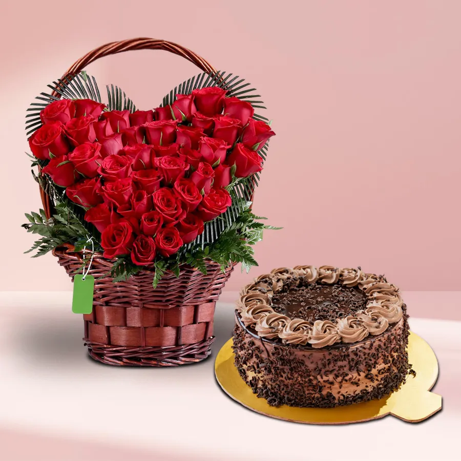 Heart-shaped basket filled with 50 red roses and a round chocolate cake.