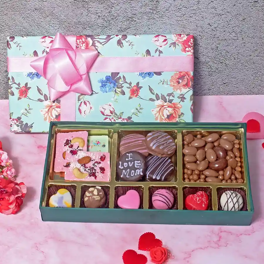 A beautifully arranged floral hamper featuring assorted chocolates, Oreo cookies, coated nuts, and a chocolate bar, designed to celebrate and delight mothers.