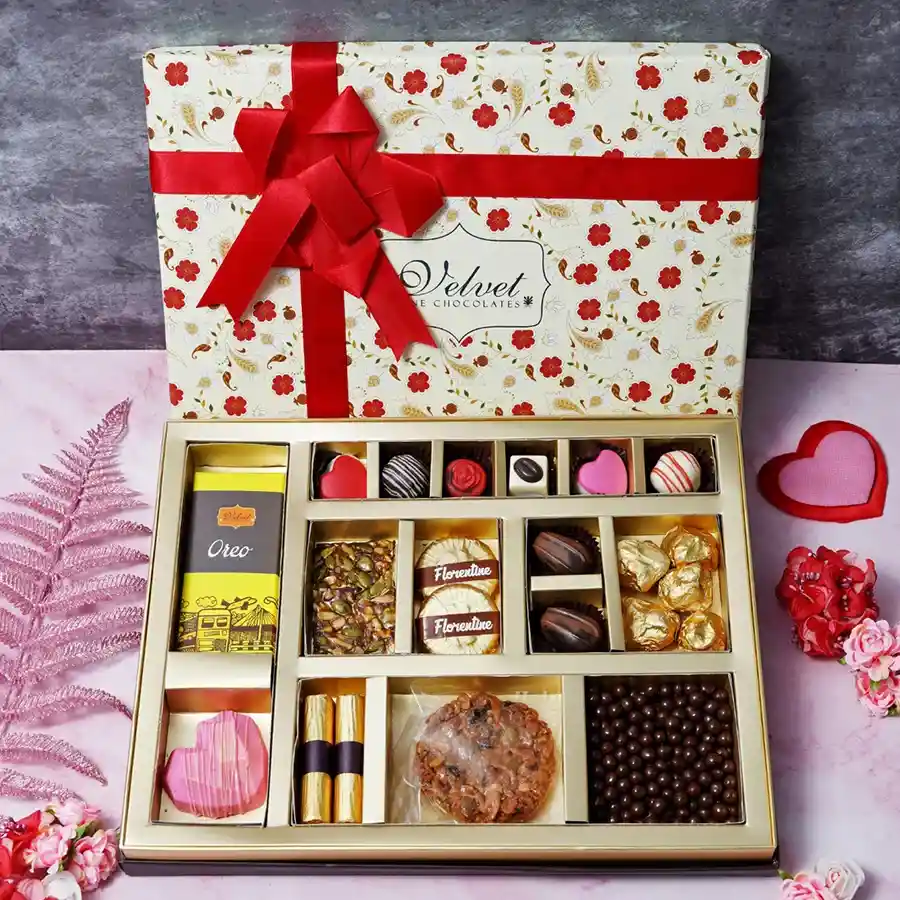 Colorful gift box filled with various chocolates, cookies, and treats for Mother's Day, including Oreo bars, nut squares, and a heart-shaped piñata.