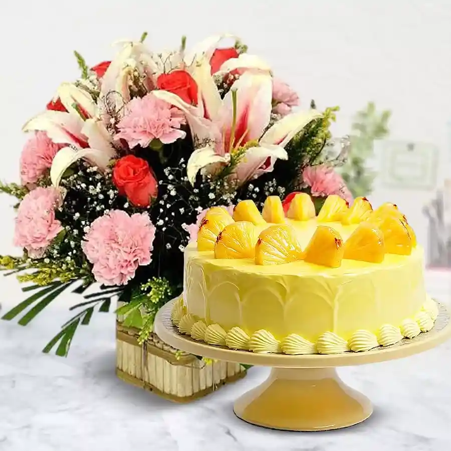 A beautiful floral basket featuring Pink Carnations, Lilies, and Orange Roses, alongside a delicious 1kg Pineapple Cake for an unforgettable gift.