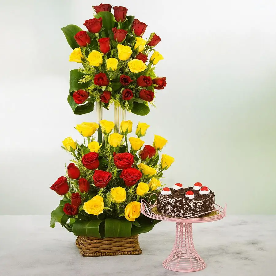 A tall basket filled with red and yellow roses accompanied by a delicious Black Forest cake, ideal for celebrating love and special moments.