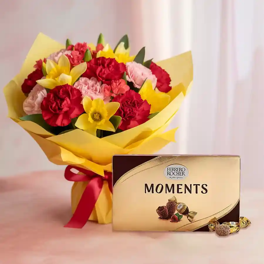A vibrant bouquet of mixed carnations accompanied by Ferrero Rocher Moments chocolate box, perfect for Mother's Day gifting.