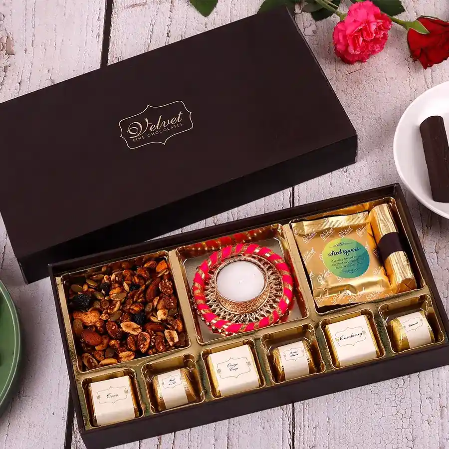 Gourmet Diwali Delight Box featuring sweet and spicy trail mix, a diya, seeds square, granola log, and assorted chocolates
