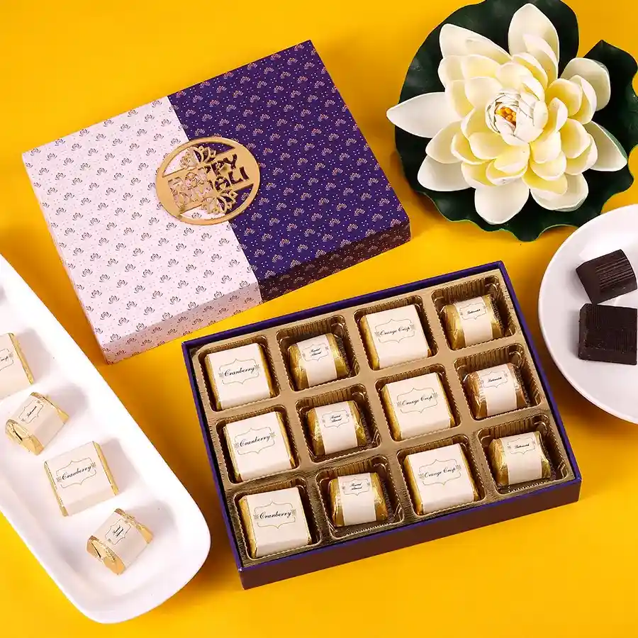 Assortment of 12 handcrafted chocolates with diverse flavors like cranberry, roasted almond, orange crisp, and butterscotch, beautifully packaged for Diwali celebrations.