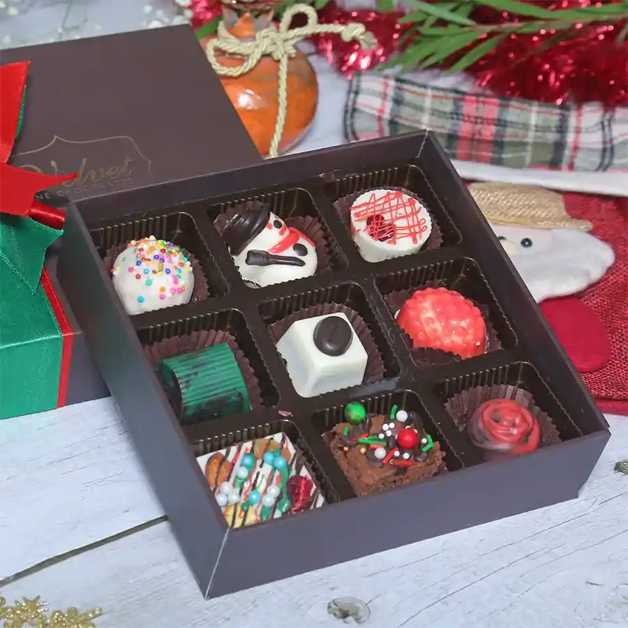 Divine Christmas Chocolaty Delicacy Box filled with assorted chocolates, brownie bites, nutty treats, and truffles on a festive background