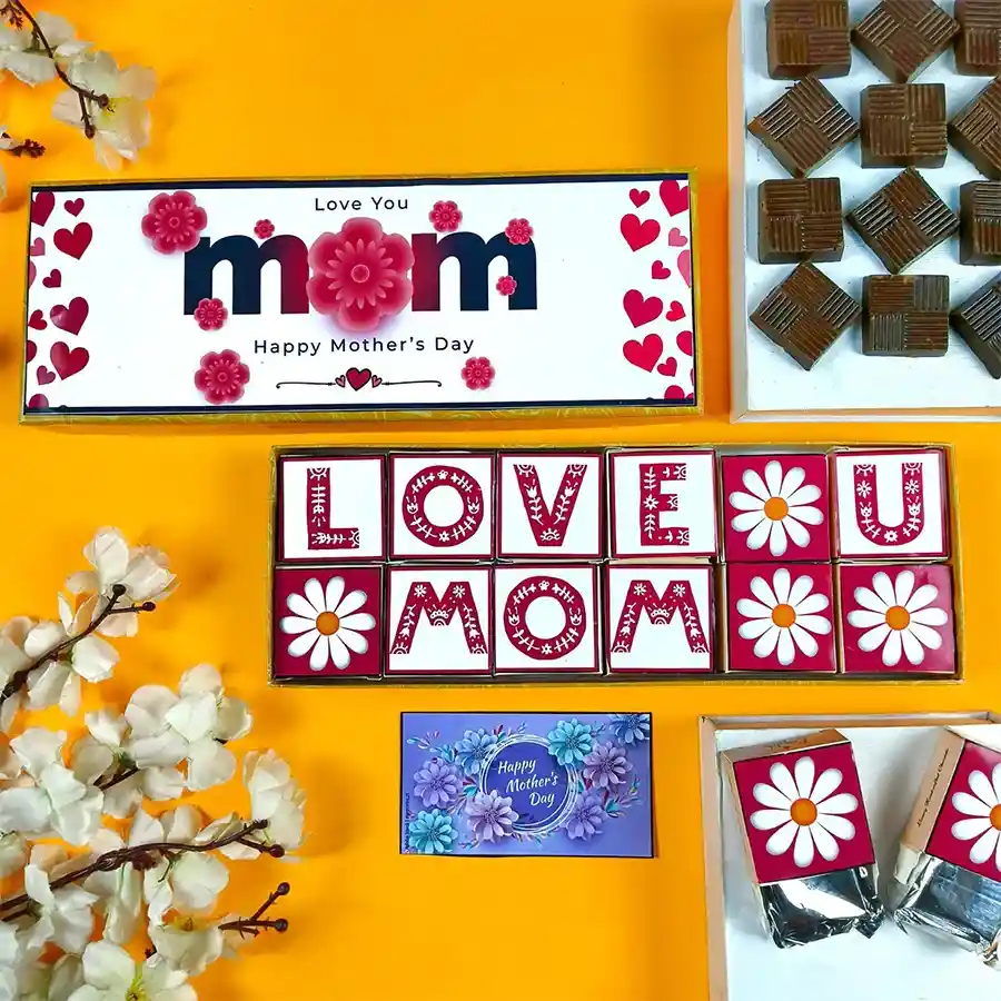 A beautifully arranged box of assorted chocolates decorated with Mother’s Day designs, accompanied by a greeting card, all set against a soft background.