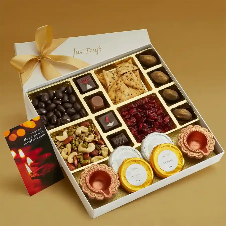 Celebration Special Treats Hamper featuring Traditional Mathri, dark chocolate almonds, masala cranberries, nut crunch mix, chocolate-coated biscuits, dates, festive truffles, and traditional diyas, all beautifully arranged in an eco-friendly packaging.