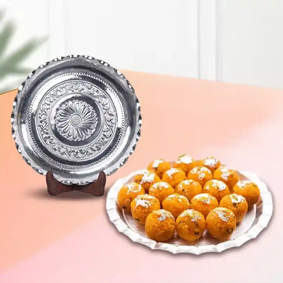 Combo of Haldirams Motichur Laddoos and silver-plated thali on a decorative background