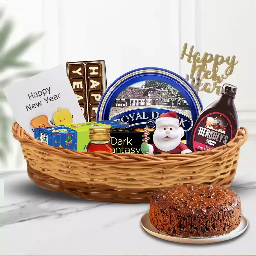 A beautifully arranged New Year hamper filled with treats including fruit cake, biscuits, honey, cookies, chocolate syrup, handmade chocolates, festive decorations, a New Year card, and a soft toy in a cozy cane basket.