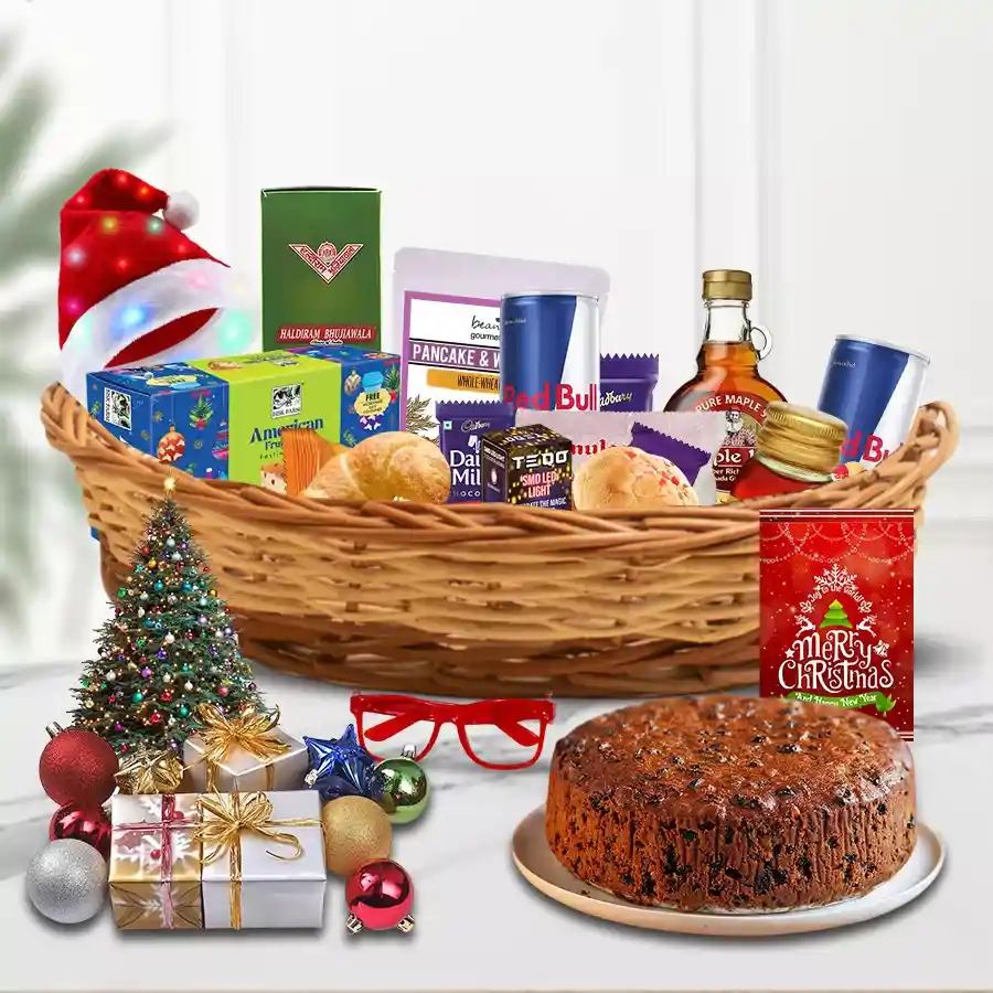 Christmas hamper filled with festive treats including fruit cake, chocolates, biscuits, syrup, and Christmas decorations in a stylish basket.