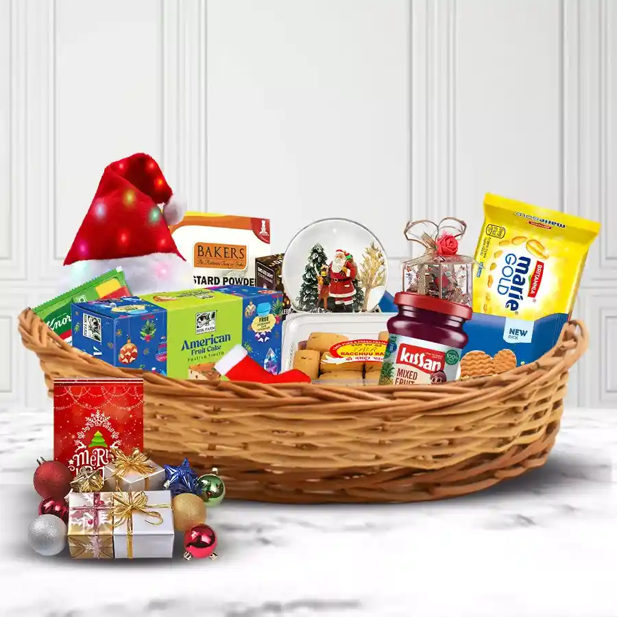 Exciting Christmas Traditional Hamper filled with festive treats including a Christmas tree, fruit cake, biscuits, tomato soup, cookies, jam, LED lights, a Santa snow globe, chocolates, custard pudding, and decorated with stockings and a Christmas card in a cane basket.