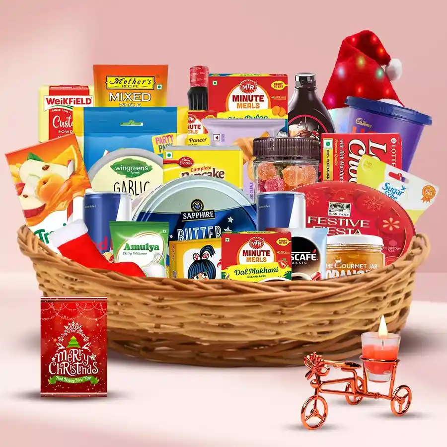 A colorful Christmas brunch basket filled with Bisk Farm Dundee Cake, Sapphire Butter Cookies, savory snacks, Red Bull, Tropicana juice, Nescafe coffee, a LED Santa hat, stockings, and a Christmas card arranged festively.