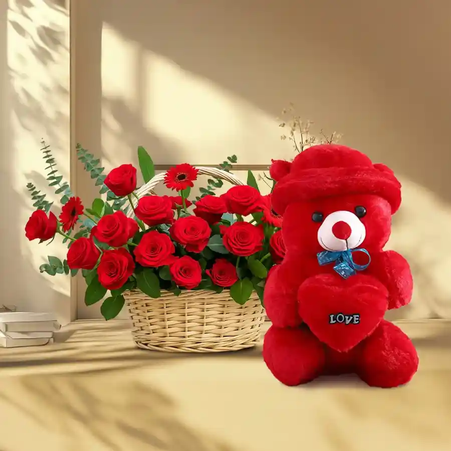 Colorful basket featuring red gerberas, red roses, and a teddy bear to bring joy and warmth.