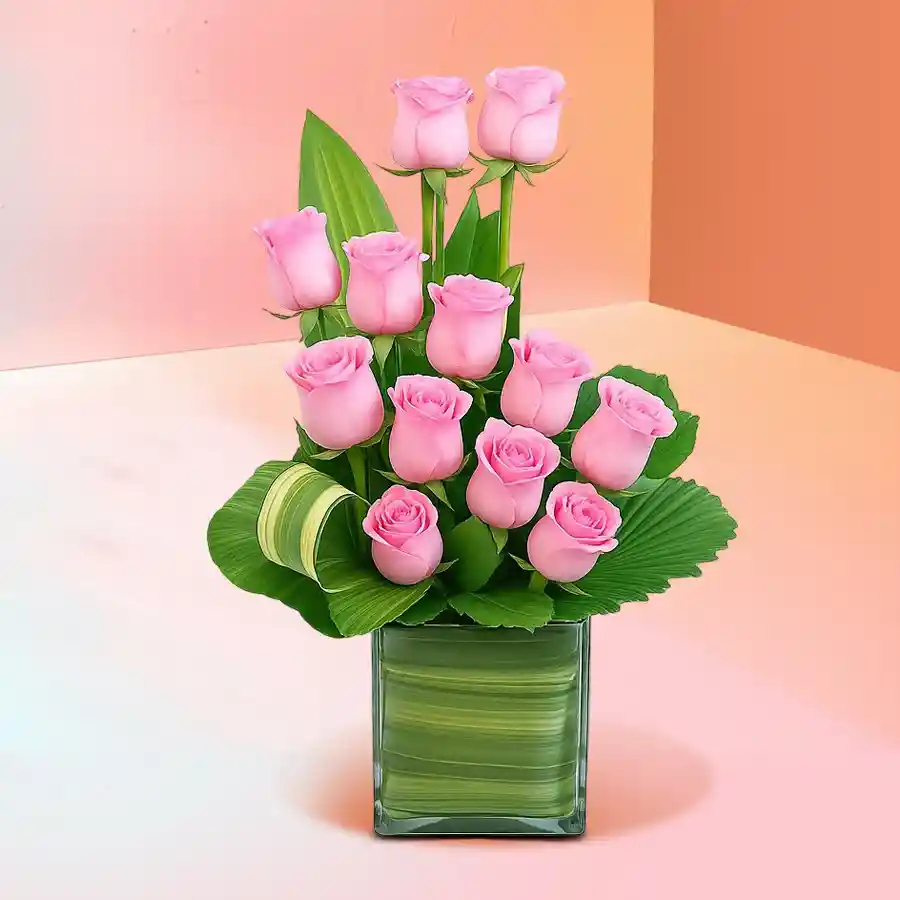 A beautiful arrangement of 12 pink roses in a medium round glass vase, ideal for gifting or home decor.