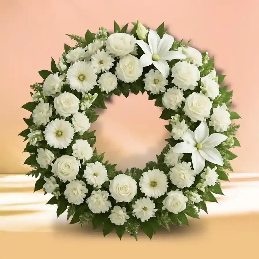 Elegant white sympathy wreath with carnations, roses, and lilies.