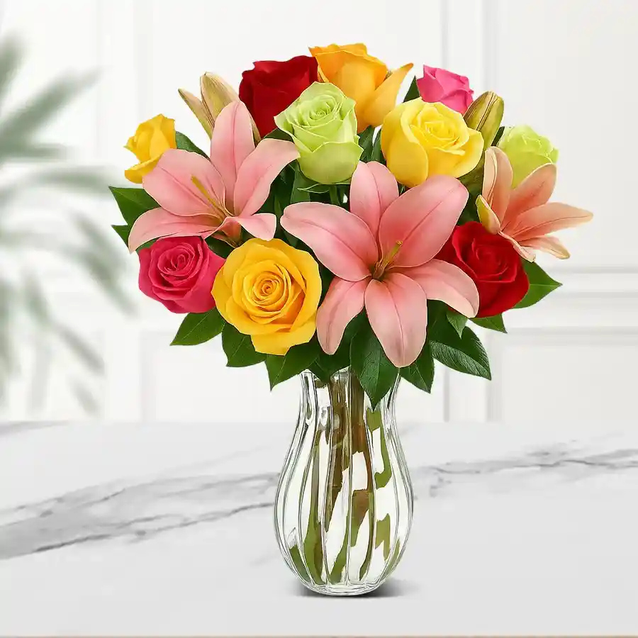 A vibrant vase arrangement featuring red, pink, white, and yellow roses alongside pink lilies, creating a stunning floral display.