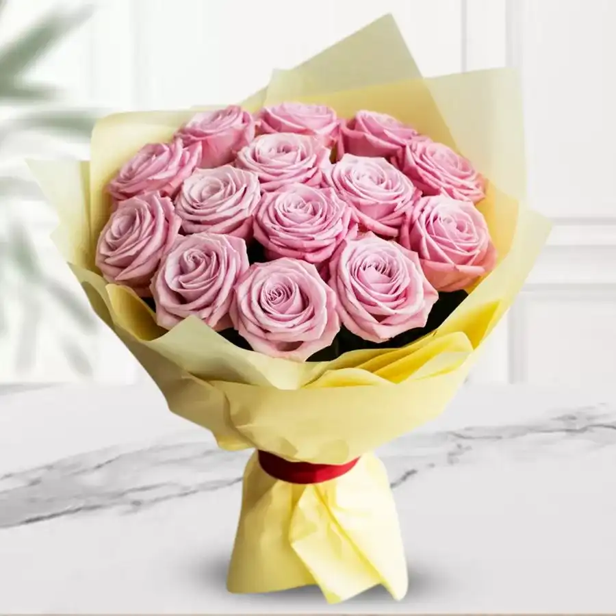 Bouquet of 12 pink roses wrapped in tissue, perfect for gifting.