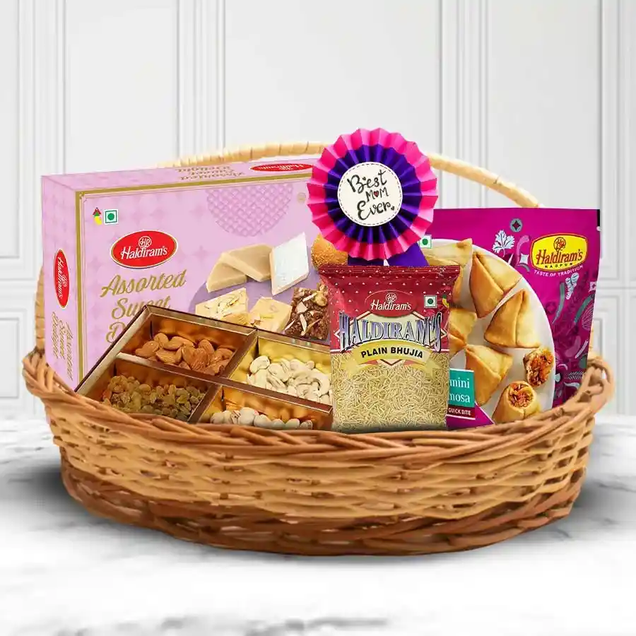Enticing Pamper Basket filled with assorted dry fruits, Haldiram sweets, bhujia, mini samosas, and a "Best Mother" award badge
