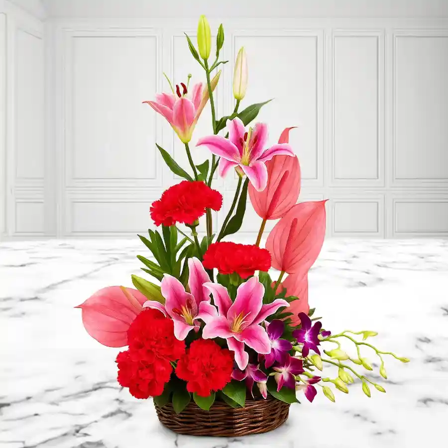 A beautiful exotic floral arrangement featuring pink anthuriums, lilies, orchids, and red carnations in a basket.